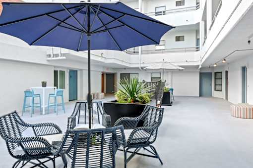 A blue umbrella is above a black table with chairs around it.