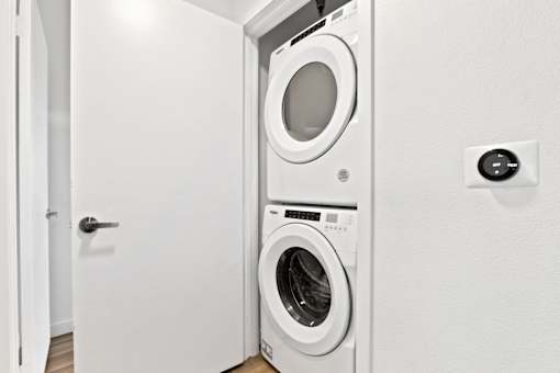A white door is open to a laundry room with a washer and dryer.
