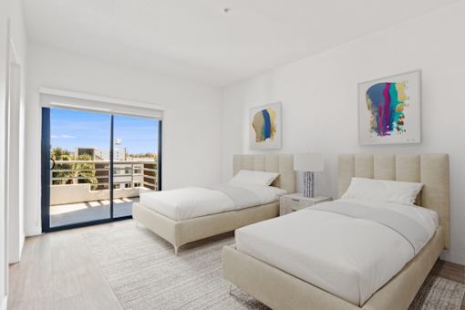 A bedroom with two beds and a balcony overlooking a building.