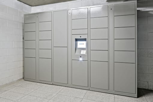 A row of grey lockers in a room with a white tiled floor.