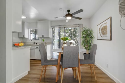 a dining area with a table and chairs and a ceiling fan