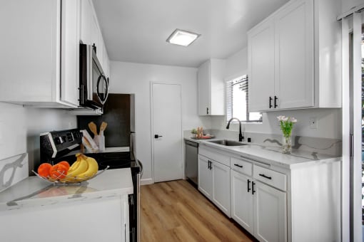 a kitchen with white cabinets and a bowl of fruit on the counter