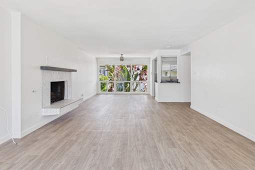 A spacious room with a fireplace and a view of the garden outside.