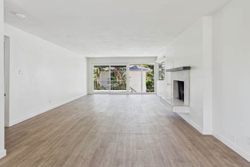 A spacious room with wooden flooring and white walls.