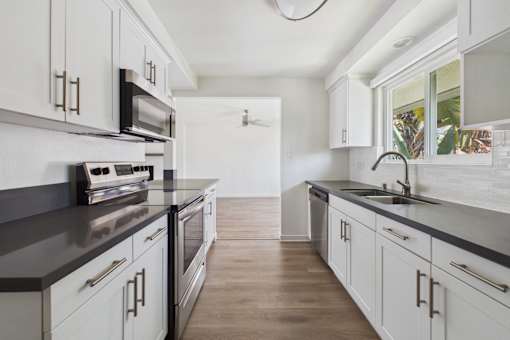 A kitchen with white cabinets and a black countertop.