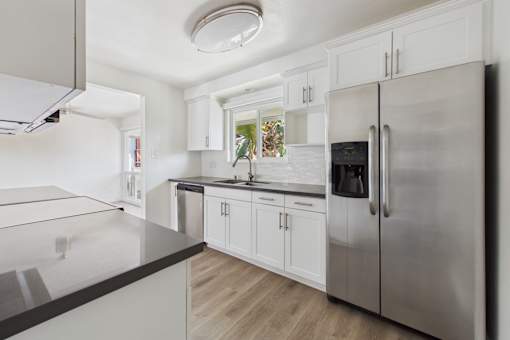 A modern kitchen with a stainless steel refrigerator and white cabinets.