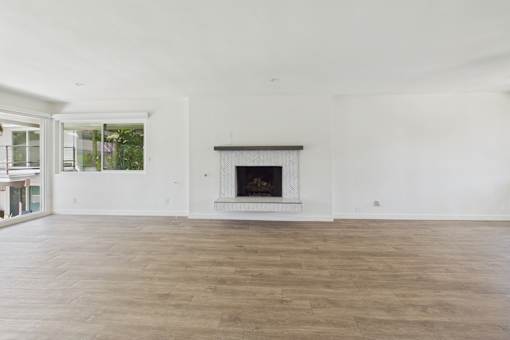 A large, empty room with a fireplace and wooden floors.
