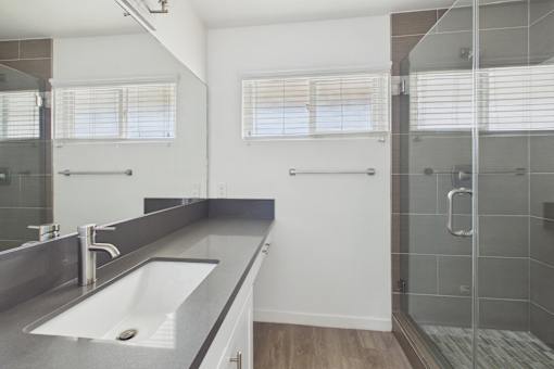 A modern bathroom with a large mirror, sink, and walk-in shower.