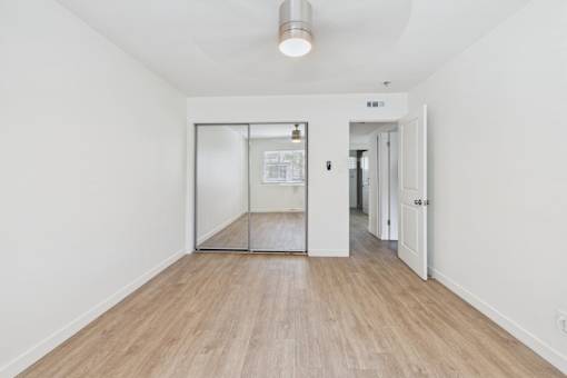 A white hallway with a wooden floor and a glass door.
