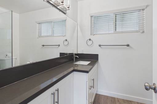 A bathroom with a sink, mirror, and towel rack.
