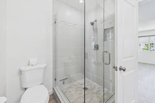 A white toilet sits next to a walk-in shower with a glass door.