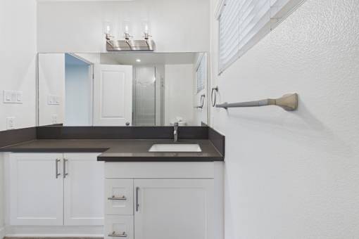 A bathroom with a sink, mirror, and cabinets.