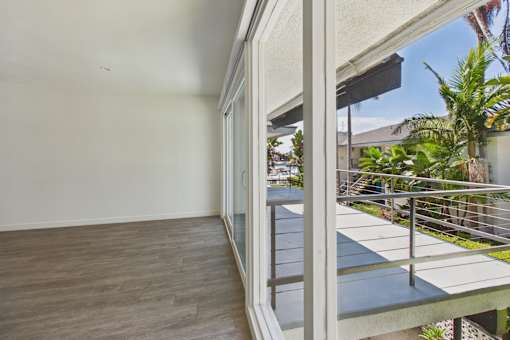 A balcony with a glass railing and a view of a building and trees.