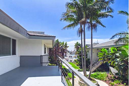 A house with a white exterior and a balcony with a metal railing.