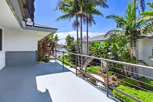 A balcony with a metal railing and a white wall.