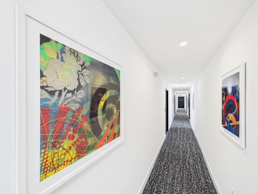 A hallway with a painting on the wall and another on the side.