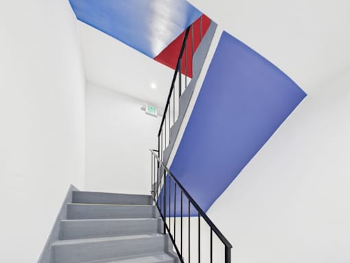 A staircase with a blue wall and a red and blue striped ceiling.
