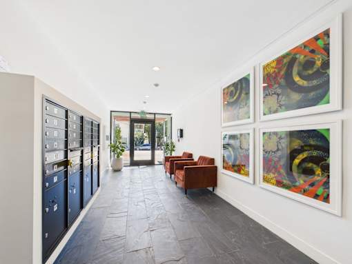 A hallway with a red chair and artwork on the wall.