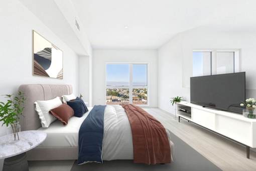 A bedroom with a bed, a television, and a plant.