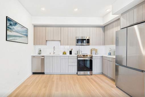 A modern kitchen with stainless steel appliances and wooden flooring.