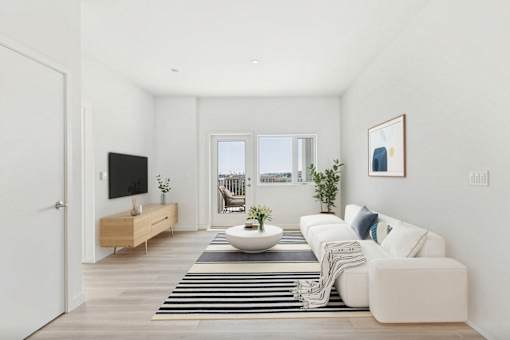 A modern living room with a white sofa, a wooden TV stand, and a large window.