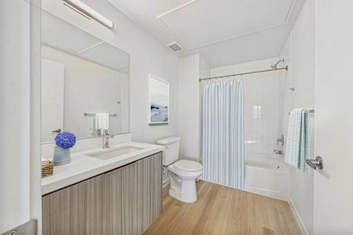 A bathroom with a white toilet, sink, and striped shower curtain.