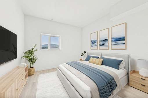 A bedroom with a large bed and a flat screen TV mounted on the wall.