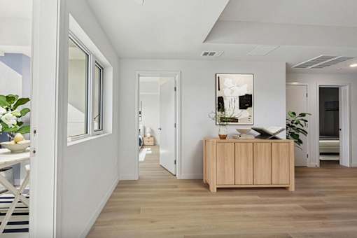 A room with a wooden floor and a wooden cabinet with a vase on top.