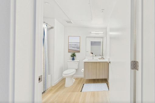A white bathroom with a toilet, sink, and a window.
