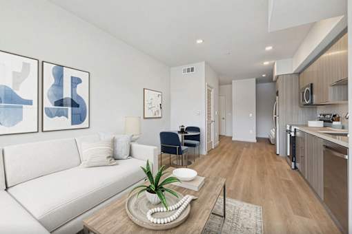 A living room with a white couch and a coffee table with a plant on it.