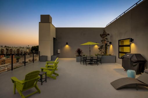 a patio with green chairs and yellow umbrellas at dusk