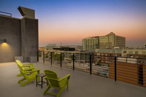 a view of the city skyline from a roof top patio with green chairs