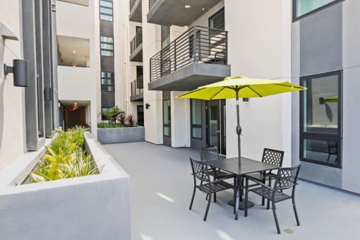 a patio with a table and chairs and a yellow umbrella