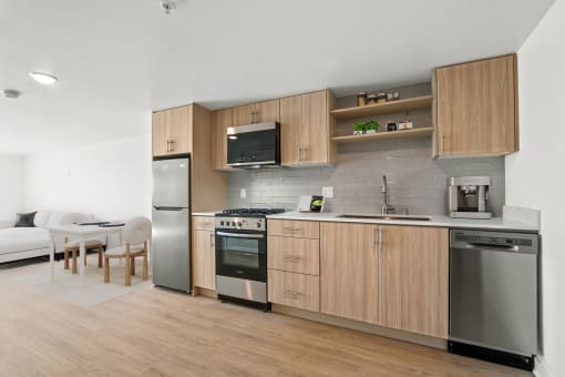 a kitchen with wooden cabinets and stainless steel appliances and a living room with a table