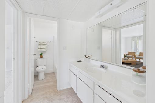 A white bathroom with a toilet, sink, and mirror.