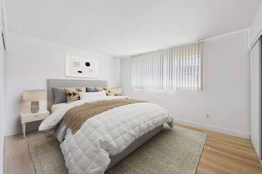 A bedroom with a large bed and a window with blinds.