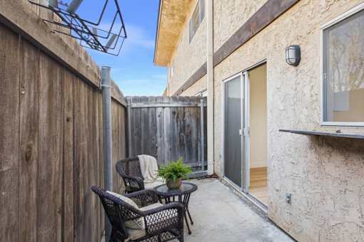 A patio with a table and chairs is surrounded by a wooden fence.
