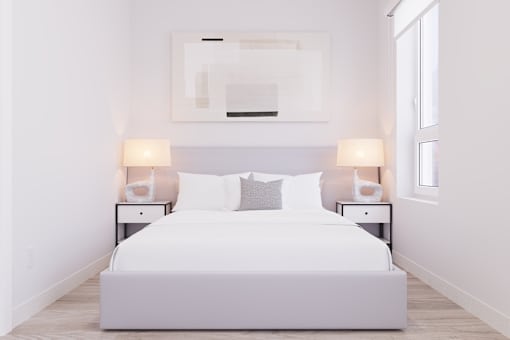 A white bed with a white headboard and two white lamps on either side.