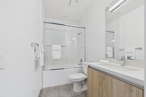 A white toilet is in a bathroom with a white sink.