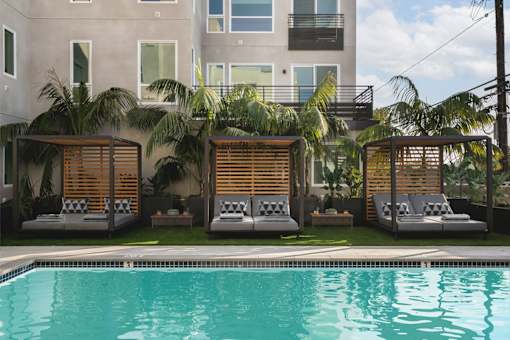 a swimming pool with lounge chairs in front of a building