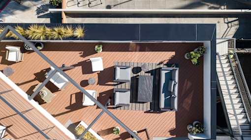 A top-down view of a rooftop patio with furniture and plants.