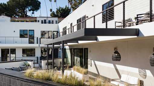 A modern white house with a balcony and a black railing.