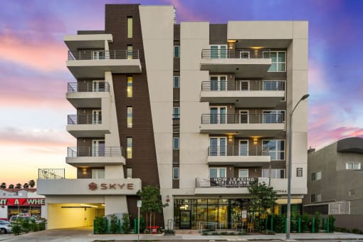 an apartment building with balconies and a sunset in the background