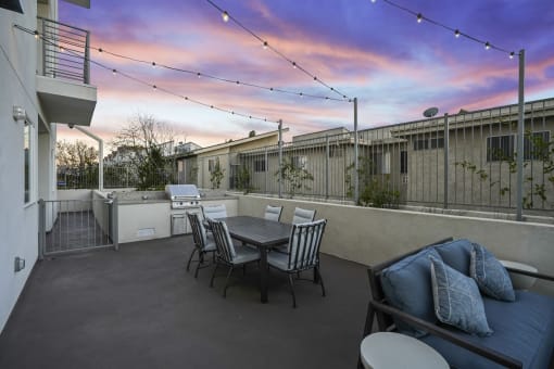 a patio with a table and chairs and a sunset in the background