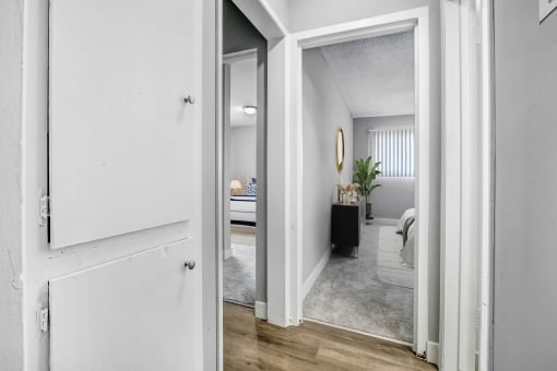 an open doorway into a bedroom with a bed and a mirror