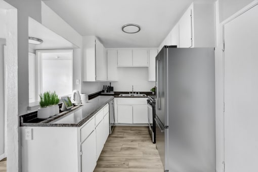 an empty kitchen with white cabinets and a stainless steel refrigerator