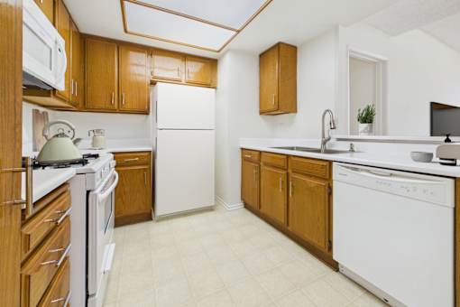 A kitchen with white appliances and wooden cabinets.
