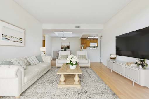 A living room with a white couch, a coffee table, and a television.