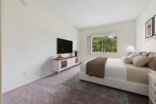 A bedroom with a bed, a television, and a window.
