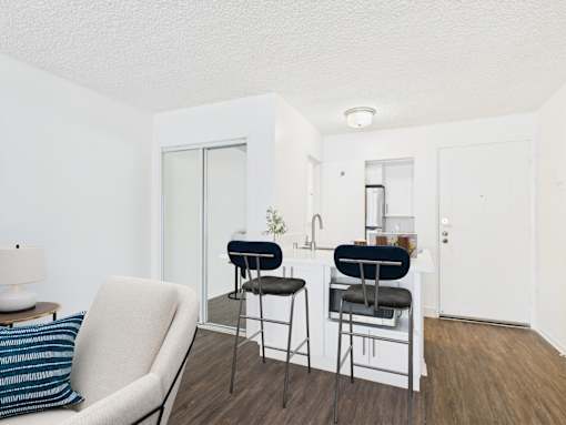 A white chair with a blue pillow is in front of a white wall.